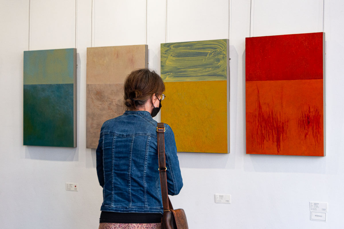 Lady looks at 4 abstract paintings by Tanja Truscott